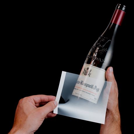 person applying wine label remover to wine bottle